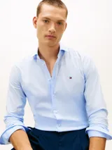 Camisa celestes de manga larga de Tommy Hilfiger, confeccionada en popelina de algodón con elastano. Presenta corte slim, cuello camisero clásico, cierre frontal con botones y el logo bordado en el pecho.