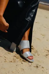 Sandalias de tacón alto con diseño de dos tiras anchas, confeccionadas en tela con estampado abstracto en tonos dorados y negros. Presentan un tacón cuadrado forrado en el mismo tejido.