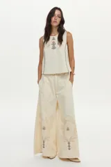 Top musculosa de denim crudo, sin mangas, con escote redondo y delicados bordados étnicos y florales multicolores en el frente.