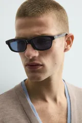 Cárdigan de punto con cuello en pico y manga larga. Presenta un diseño de ajuste relajado con cierre frontal de botones y acabados en rib con efecto doble en color azul a contraste sobre la base color topo.