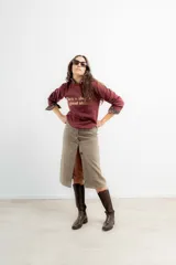 Falda midi de tiro alto confeccionada en tejido tweed con patrón de espiga en tono marrón. Presenta un diseño recto y cierre frontal con botones.