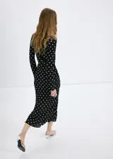 Vestido largo negro con estampado de lunares blancos, de corte recto, escote redondo y mangas largas.