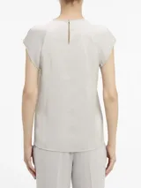 Blusa de satén color gris claro, con cuello redondo y abertura en forma de gota. Tiene mangas cortas con costuras en los hombros y cierre con broche en la espalda.