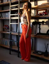 Pantalón naranja de crepe elastizado, corte recto, con bolsillos delanteros y apliques de botones metálicos.