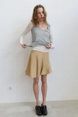 Falda corta de tiro medio con diseño asimétrico en el bajo y cierre lateral con cremallera oculta.