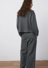Buzo gris oscuro de piqué, de cuello redondo y manga larga con puños ajustados, con detalle de costura horizontal en el pecho.