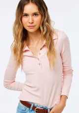 Remera polo de manga larga en color rosado, con cuello y tapeta de botones frontales.