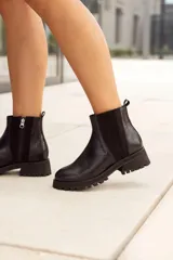 Botas Chelsea de cuero negro, caña corta, con suela track gruesa y cierre de cremallera lateral.