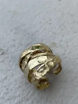 Anillo de diseño enlazado con textura irregular, realizado a mano en bronce. Presenta un diseño abierto que permite regular su tamaño con suavidad.