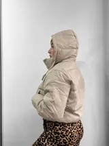 Campera puffer color beige con cuello alto, cierre frontal con cremallera y bolsillos laterales.