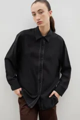 Camisa de corte holgado y diseño clásico, confeccionada en tela satinada con un sutil estampado floral tono sobre tono. Presenta cuello camisero, cierre frontal con botones y mangas largas con puños rectos.