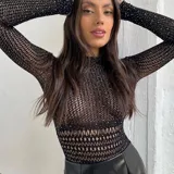 Body de red negro con mangas largas, cuello redondo y apliques de strass brillantes en toda la prenda. Presenta un diseño ajustado al cuerpo con una textura calada.