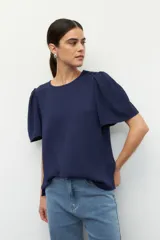Blusa azul marino con mangas abullonadas y botones decorativos en los hombros.