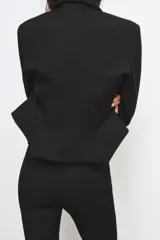 Blazer corta negra de la colección Zara Woman, con cuello solapa de muescas y manga larga. Presenta detalles de pespuntes marcados y forro interior a tono. Cierre frontal con botones.