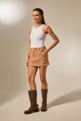 Minifalda de gamuza color camel, de corte recto, con talle alto y cierre frontal con un botón dorado.