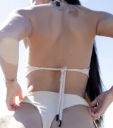 Top de bikini negro con breteles finos que se cruzan en el frente y se atan en la espalda.