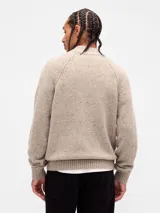 Buzo de punto con cierre frontal completo, confeccionado en lana con textura jaspeada. Presenta cuello alto acanalado, mangas raglán y puños y ruedo elásticos.