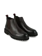 Bota tipo Chelsea de cuero color marrón oscuro, con paneles elásticos laterales y suela de goma dentada estilo track.