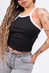 Top de rib ajustado al cuerpo, con cuello y sisas en contraste blanco. Presenta un diseño sin mangas con espalda estilo nadadora y una pequeña etiqueta decorativa en el ruedo.