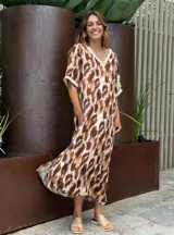 Vestido largo con estampado animal print en tonos marrones y blancos, con cuello en V y mangas cortas con ribete blanco.
