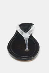 Sandalia plana tipo ojota con suela negra y tira de vinilo transparente.