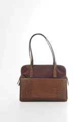 Cartera de hombro tipo portafolio confeccionada en cuero vacuno, con diseño estructurado que combina marrón liso y un panel frontal en cuero texturizado color mostaza. Posee doble asa larga y cierre superior.