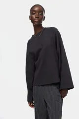 Buzo oversized de punto interlock pesado en color negro, con cuello redondo y mangas largas amplias.