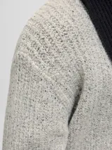 Sweater de punto con cuello redondo y manga larga, de calce holgado. Presenta textura acanalada y puños elásticos, confeccionado en un tejido melange de tono claro.