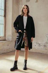 Tapado de lana color beige, de corte recto y largo medio, con solapas clásicas, cierre frontal de botones y bolsillos laterales amplios.