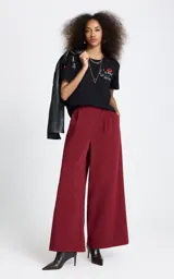 Remera negra de algodón con cuello redondo y mangas cortas. Presenta un bordado frontal con la frase 'L'amour est déclaré' acompañada de un diseño de labios rojos, y un detalle bordado adicional en la manga derecha.