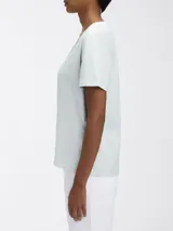 Remera Calvin Klein de manga corta y cuello en V, color verde menta pálido. Presenta una etiqueta con el logo de la marca en la parte posterior del cuello.