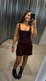 Vestido corto de color bordó con textura arrugada, escote cuadrado y falda con volado en el ruedo.