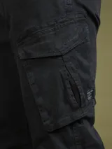 Pantalón cargo negro de sarga de algodón con spandex, con bolsillos laterales con solapa y etiqueta con el logo de la marca en uno de ellos.