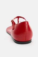 Sandalia plana de piel en color rojo, con diseño de tiras tipo thong que incluye posición para el dedo, cierre mediante hebilla metálica en el tobillo y suela fina.