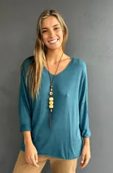 Jersey de punto color turquesa, con cuello en V, diseño oversize y mangas tres cuartos con dobladillo. Confeccionado en tejido liviano con caída fluida.