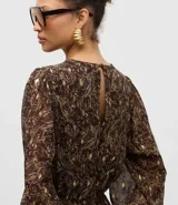 Vestido corto de chiffon con estampado paisley en tonos marrones y detalles metalizados dorados. Presenta mangas largas con puños elásticos, cuello redondo y falda con caída fluida.