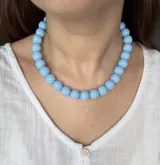 Gargantilla de cuentas esféricas celestes brillantes dispuestas en una sola hilera.