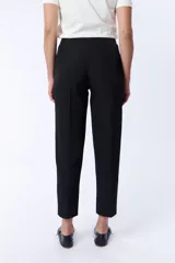Pantalón de vestir negro, corte carrot con botón y cierre frontal.