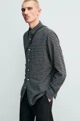 Camisa de corte regular fit confeccionada en una mezcla de lana y algodón. Presenta un diseño de cuadros pequeños, cuello solapa, manga larga con puños abotonados y cierre frontal con botones. Incluye un bolsillo en el pecho.