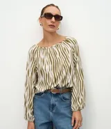 Blusa de viscosa con estampado animal print de cebra en tonos verde oliva y blanco, con escote bote y mangas largas abullonadas con puños elásticos.