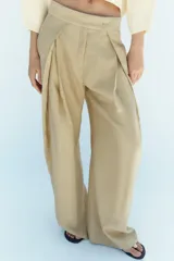 Pantalón de tiro medio color beige perteneciente a la colección ZW Collection, de corte ancho y recto, con detalle de pliegues frontales y cierre con cremallera y ganchos metálicos.