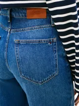 Jean de Tommy Hilfiger confeccionado en denim rígido, con corte de pierna ancha y talle alto. Presenta un diseño clásico de cinco bolsillos, cierre de cremallera con botón y un sutil efecto desteñido en muslos y rodillas.
