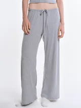 Pantalón de dormir de corte recto y holgado, confeccionado en tejido suave con textura acanalada. Presenta cintura elástica con cordón ajustable y bolsillos laterales.