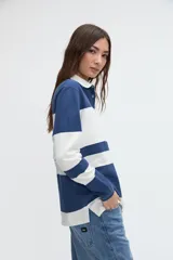 Remera polo de manga larga de algodón lavado, con diseño de rayas horizontales anchas en azul y blanco, cuello y cartera de botones en color blanco, y pequeños tajos laterales.