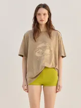 Remera oversize de corte cuadrado, color verde, con cuello redondo y estampa retro centrada en tono amarillo.