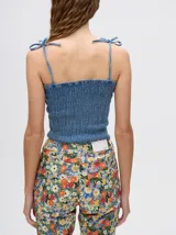 Top crop de tela denim con efecto fruncido, breteles finos ajustables con lazos y diseño entallado al cuerpo.