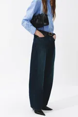 Jean de denim en tono azul oscuro con efecto deslavado, diseño de piernas curvas y corte holgado.