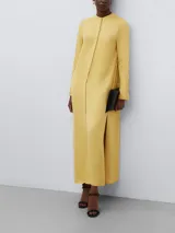 Vestido largo de corte recto y silueta fluida, confeccionado en viscosa. Presenta cuello mao con cierre de botón oculto, mangas largas con puños abotonados y aberturas laterales en el ruedo.