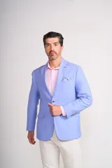 Blazer sport de corte entallado en color celeste, con solapas clásicas, cierre frontal de un botón y bolsillos laterales con solapa. Presenta un pañuelo de bolsillo estampado y botones decorativos en los puños.