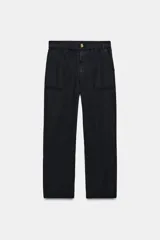 Pantalón negro de tiro medio con cintura elástica y pernera holgada. Cuenta con bolsillos de plastrón en el delantero y cierre frontal con cremallera y botón.